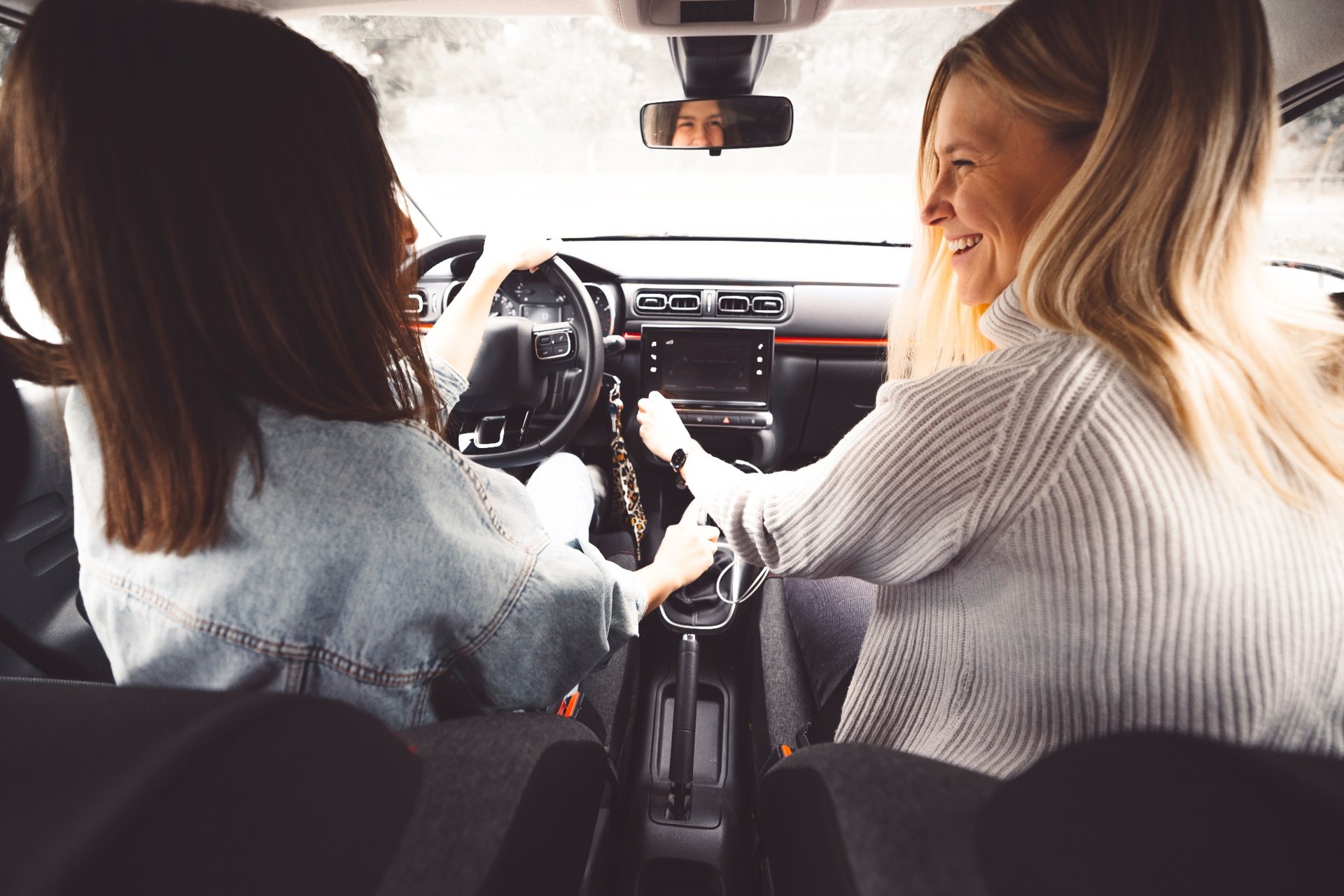 Two women smiling and chatting inside a car