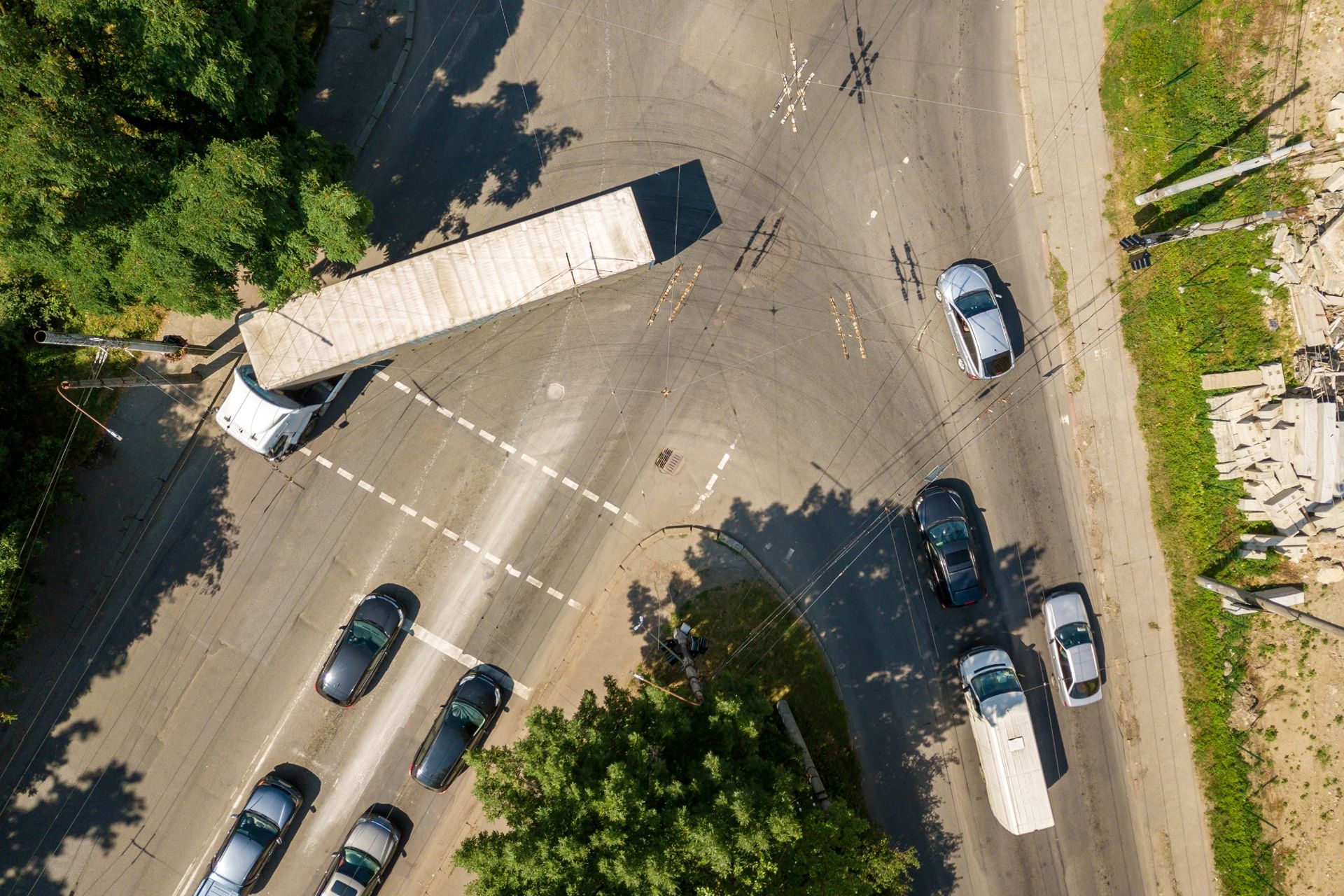Aerial view of a semi-truck turning at a busy street intersection with several cars waiting