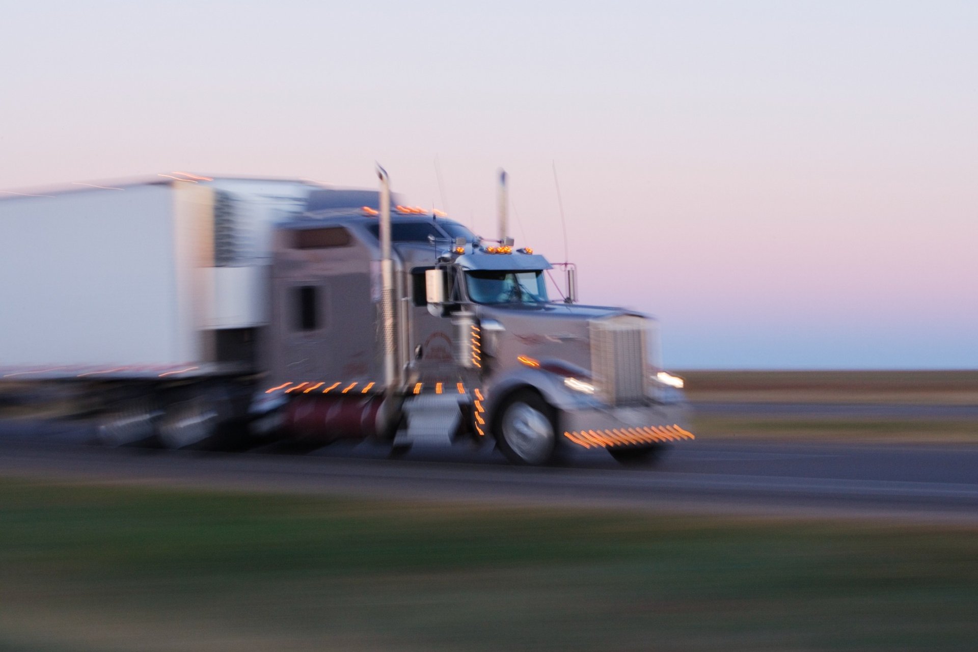 Blurred motion photo of a semi-truck driving on Texas Highway 287 during sunrise