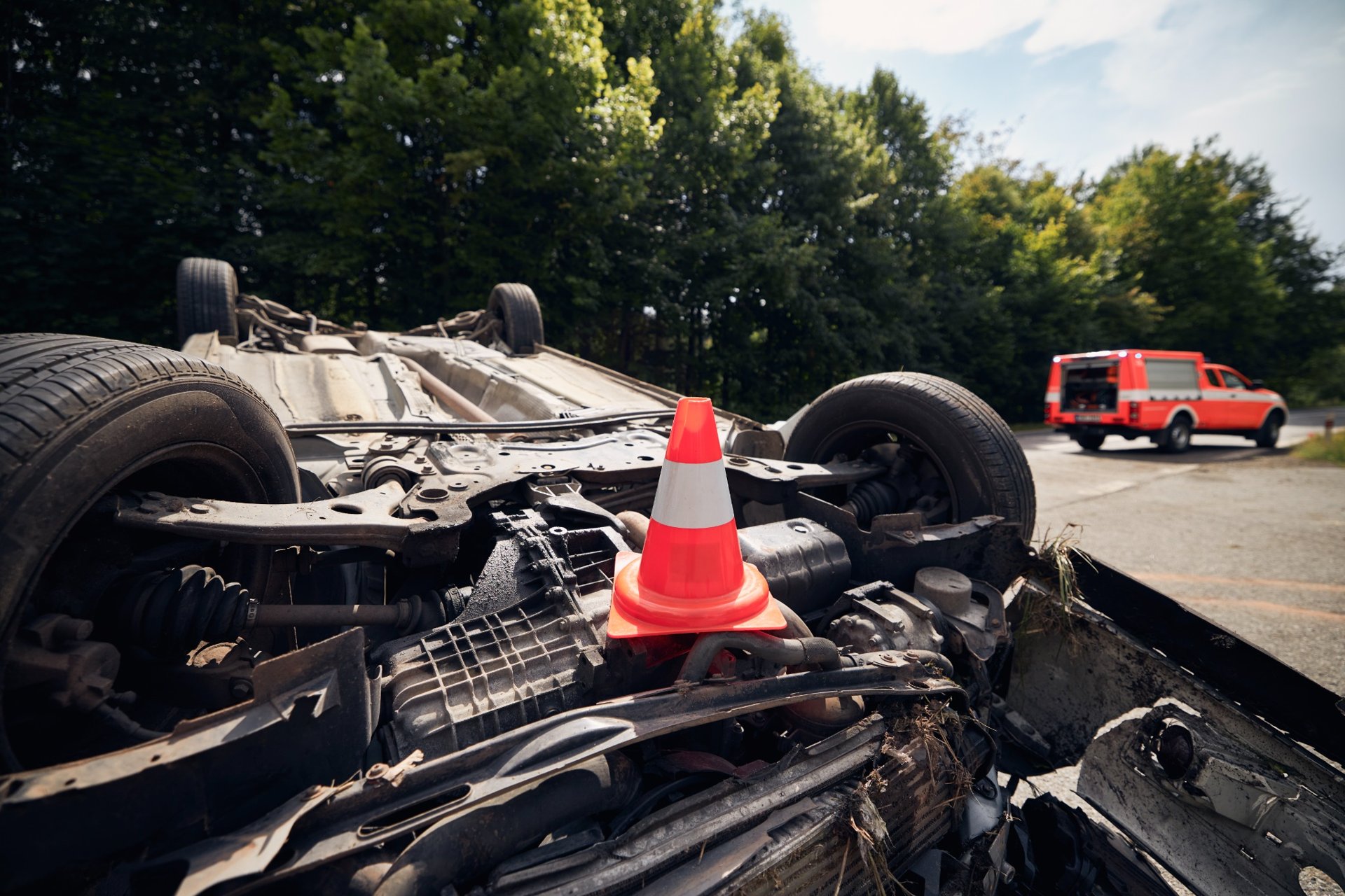 Overturned car with a safety cone placed on its undercarriage after a traffic accident