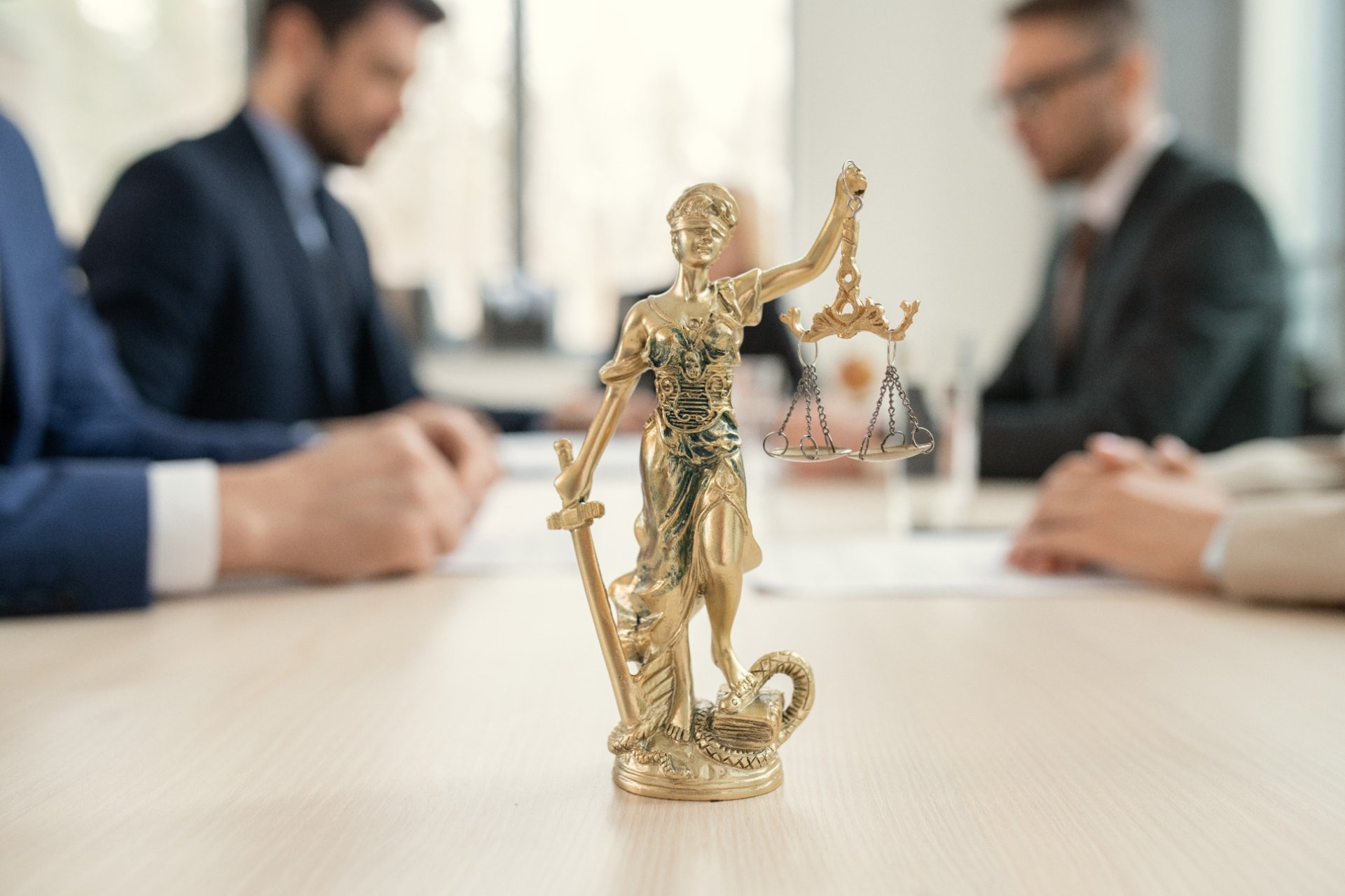 Lady Justice statue in focus during a legal negotiation meeting