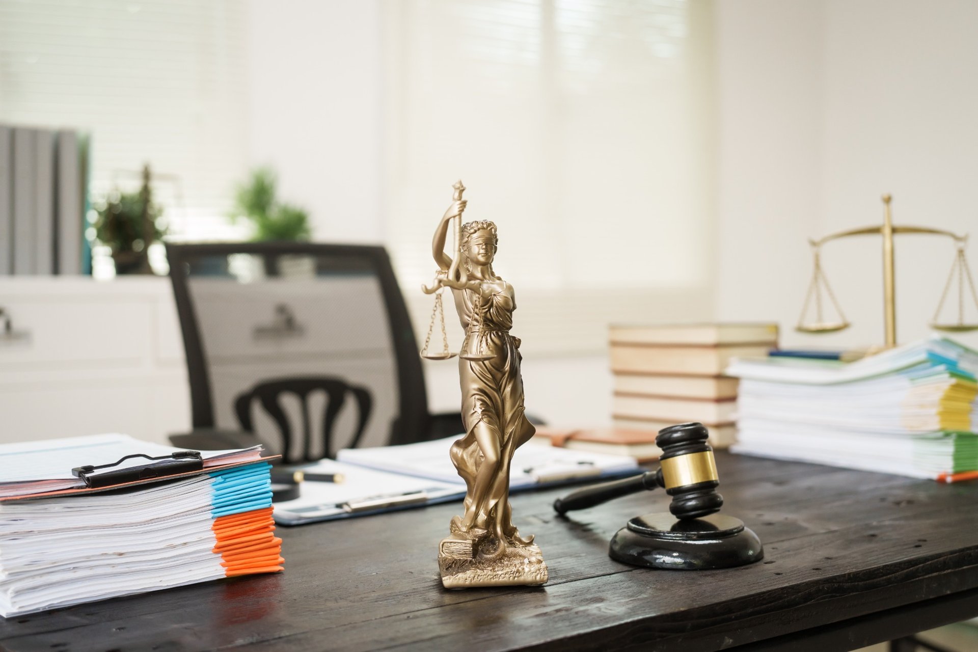 Legal office desk with Lady Justice statue, gavel, and documents